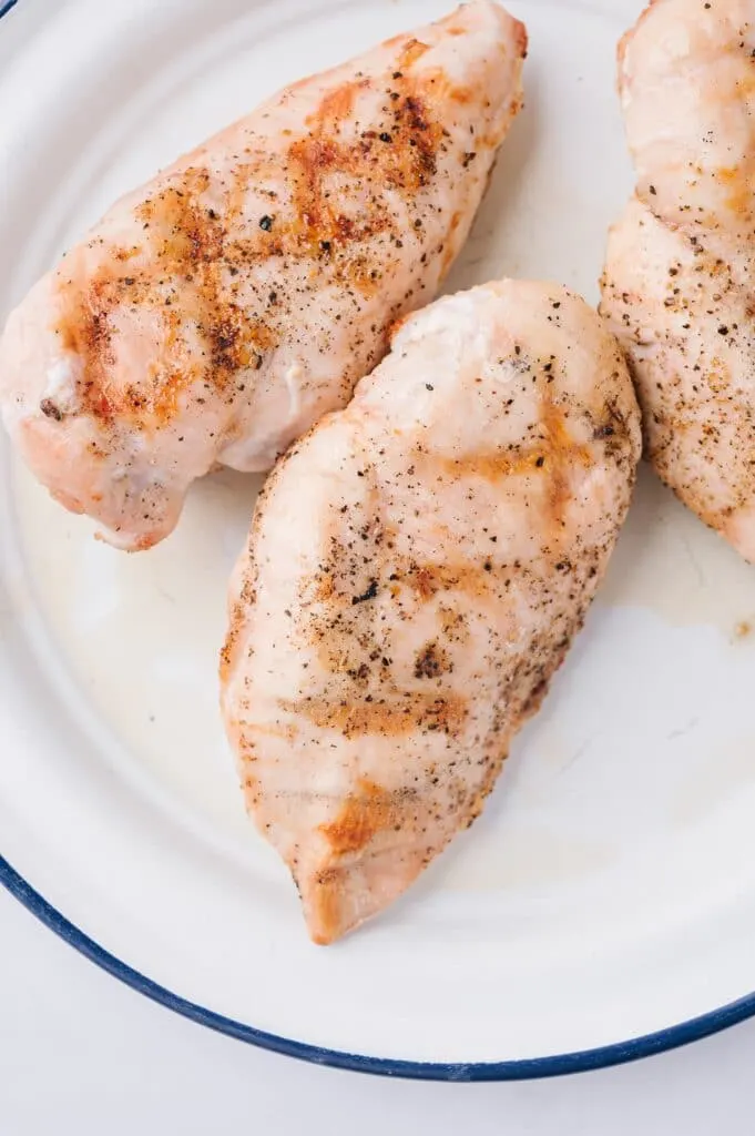 grilled chicken breasts on a plate, ready to top caprese chicken