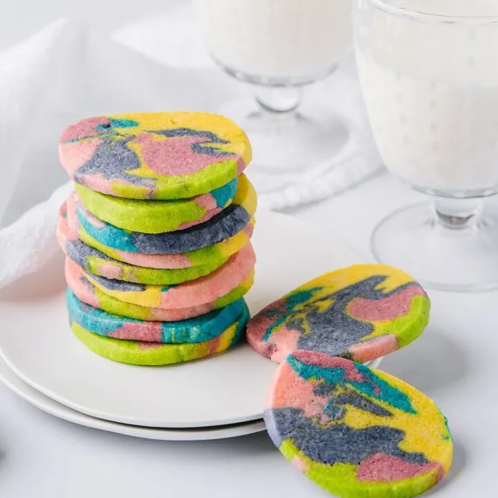 tie dye cookies on a plate with glasses of milk in the background