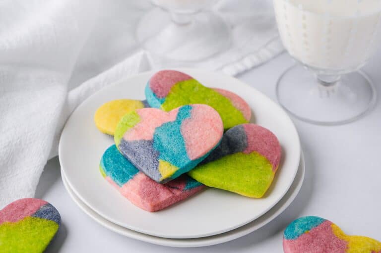 tie dye cookies on a plate with glasses of milk in the background