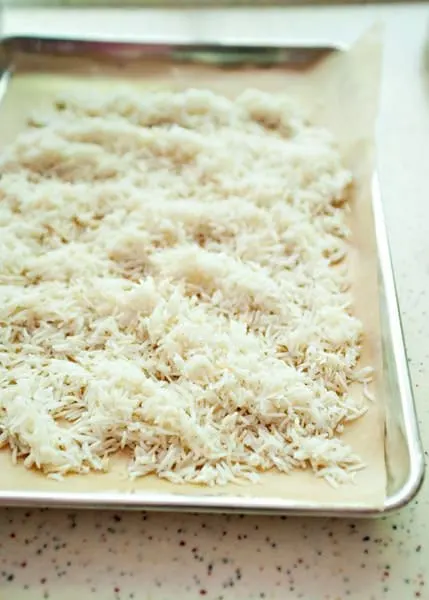 rice spread over parchment paper lined baking sheet for mediterranean rice salad
