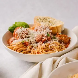 spaghetti and meatballs on a plate with garlic bread