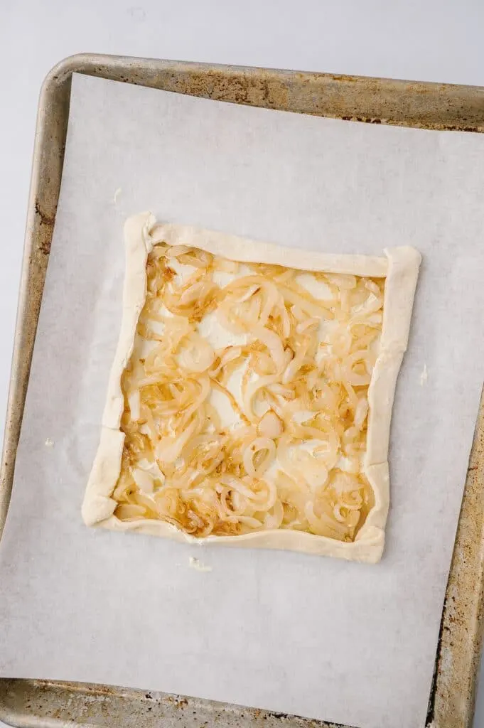 tart with onion mixture on parchment paper