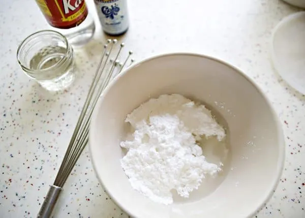 ingredients for sugar cookie glaze in a bowl with a whisk