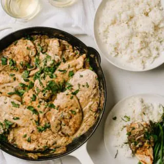 skillet of boursin chicken with glasses of wine and bowl of rice with a plate of chicken with green beans and rice