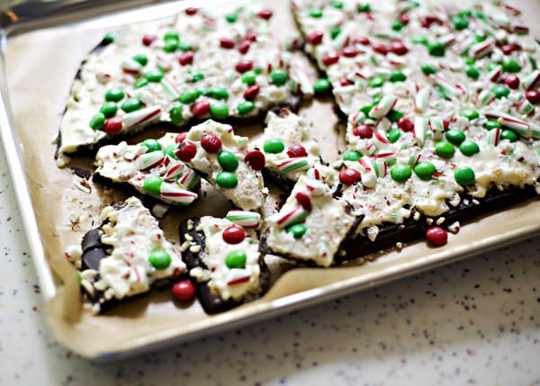 christmas chocolate bark broken into pieces on a parchment paper lined cookie sheet