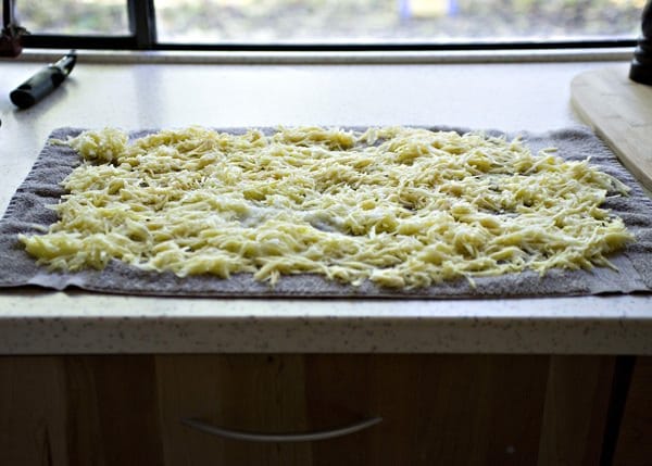 shredded potatoes spread out on a dish towel for potato latkes
