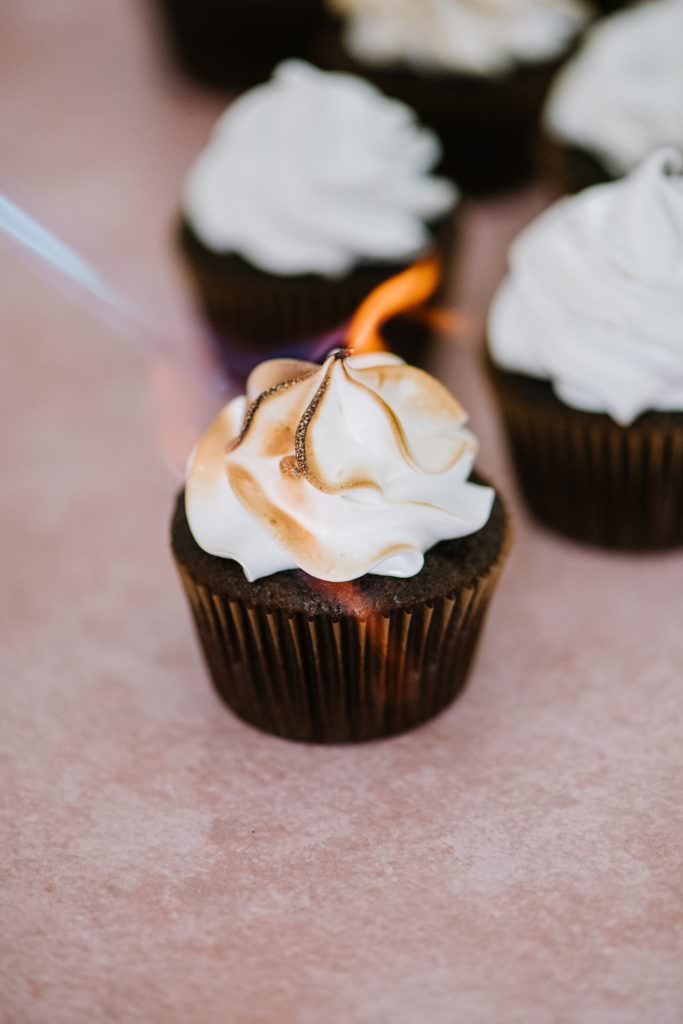 kitchen torch burning italian meringue icing on a chocolate cupcake