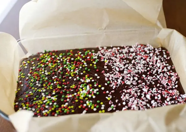 chocolate fudge topped with sprinkles in a parchment paper lined pan