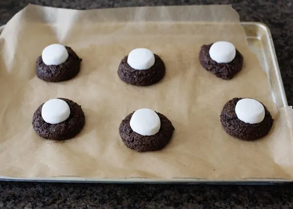 surprise cookies with marshmallows on a parchment paper lined cookie sheet