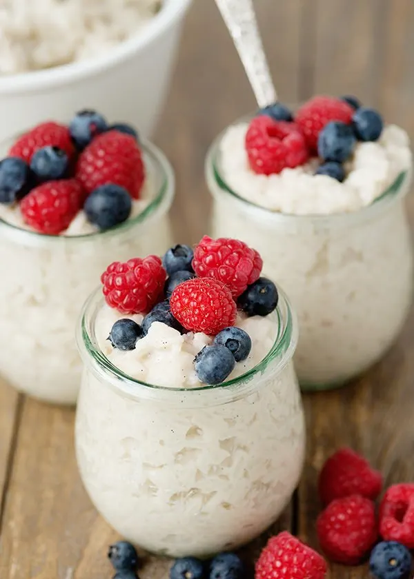 3 parfait glasses of vegan rice pudding topped with fresh berries