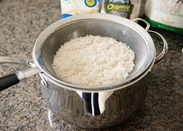 cooked rice in a strainer to make vegan rice pudding