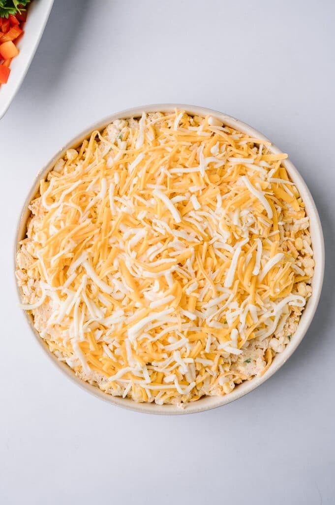 hot corn dip covered with cheese in a bowl