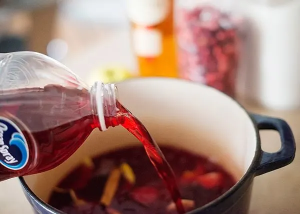 pouring cranberry juice into ingredients for cranberry calvados cocktail