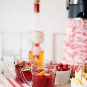 cranberry calvados cocktail on a table with cranberries, lemons and calvados
