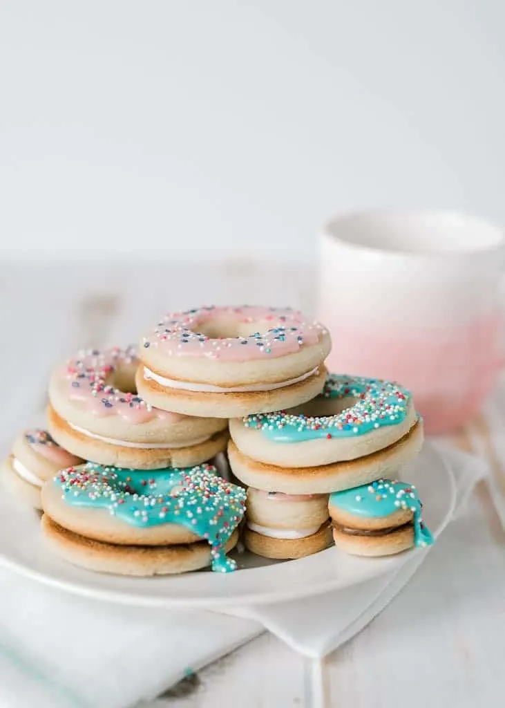 doughnut sandwich cookies on a plate with a coffee cup