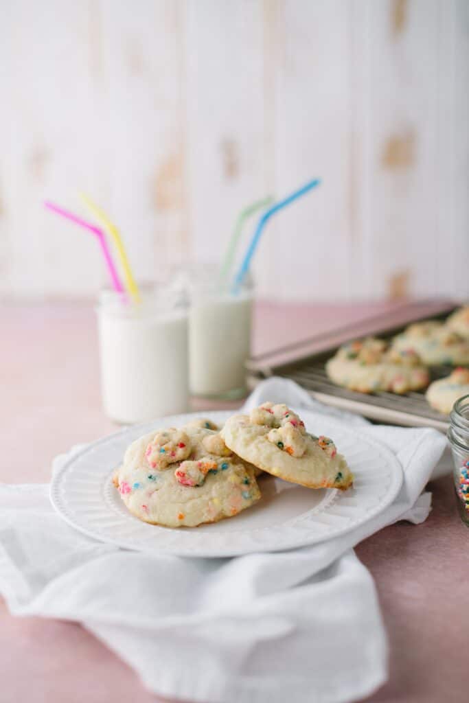 funfetti crumble coolies on a plate with glasses of milk and cookies in the background