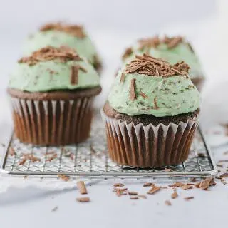 4 mint chocolate chip cupcakes on a rack with chocolate shavings