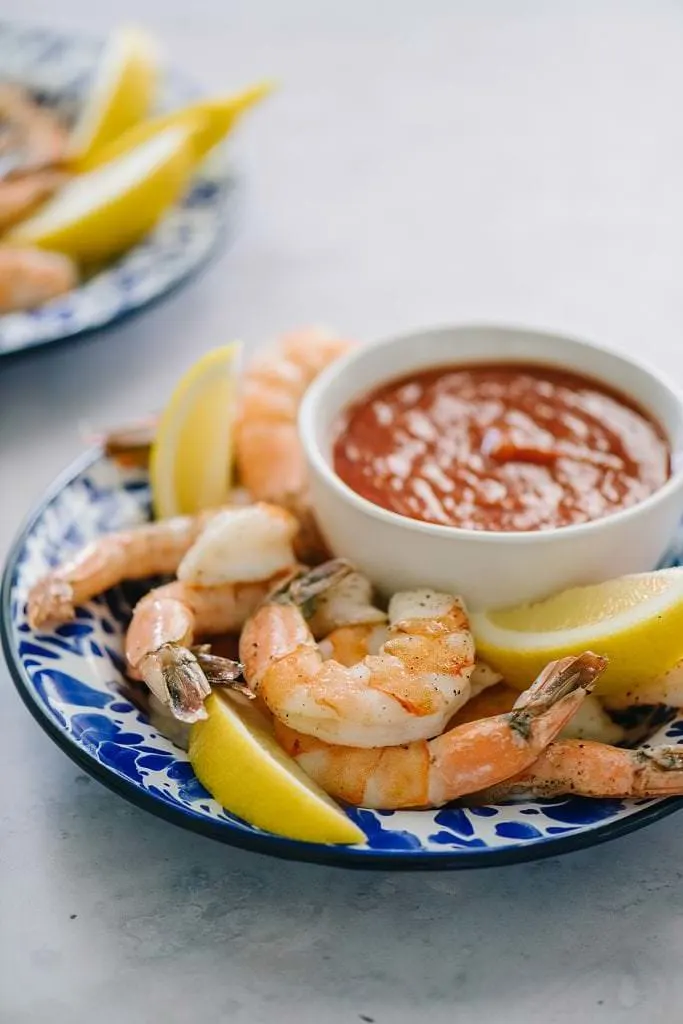 two plates with roasted shrimp and cocktail sauce