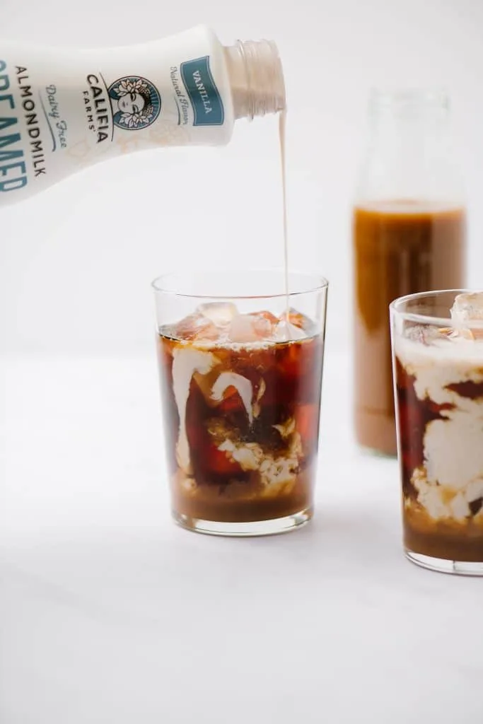 cream pouring into an iced coffee
