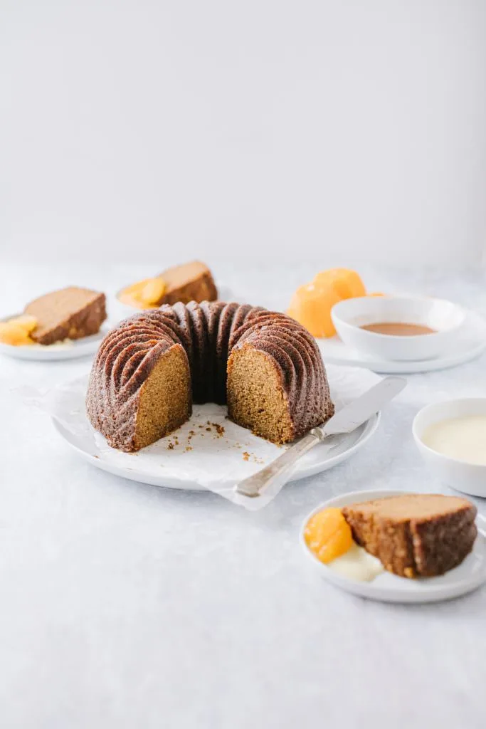 orange gingerbread bundt cake on a plate with slices around it