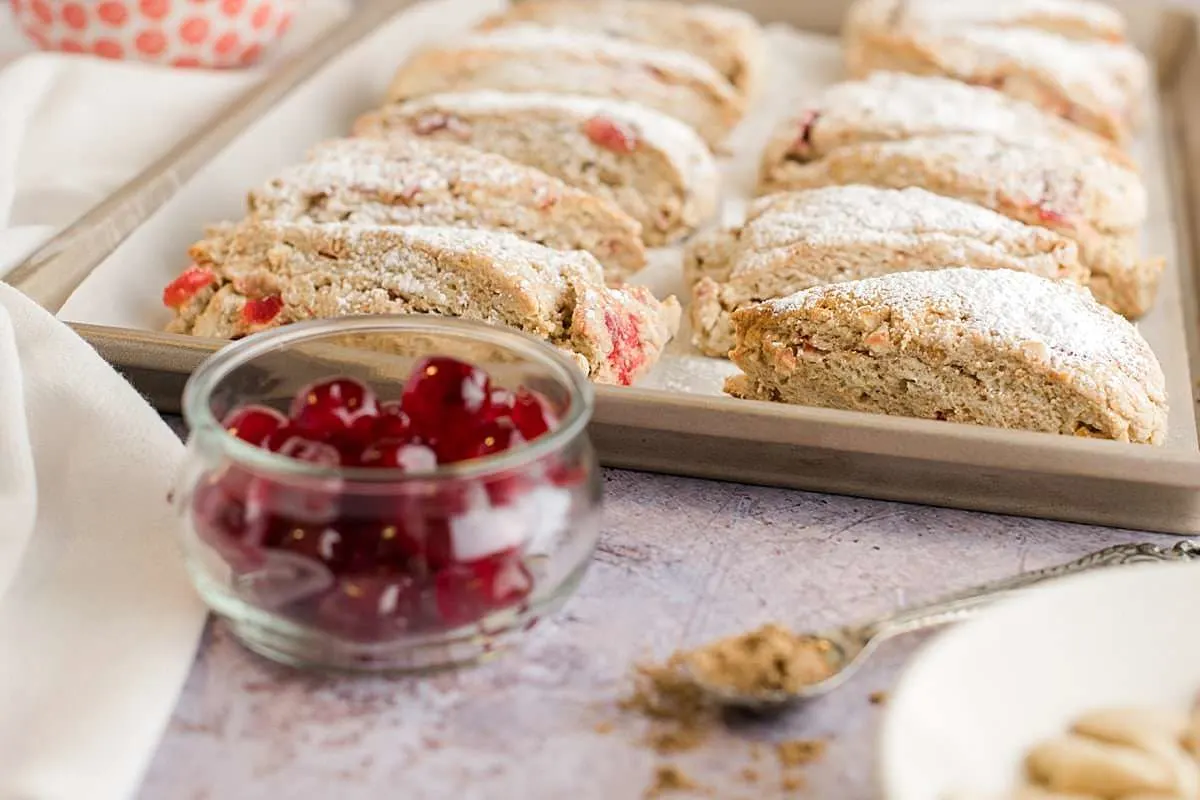 christmas stollen scones on a baking sheet with a bowl of glace cherries