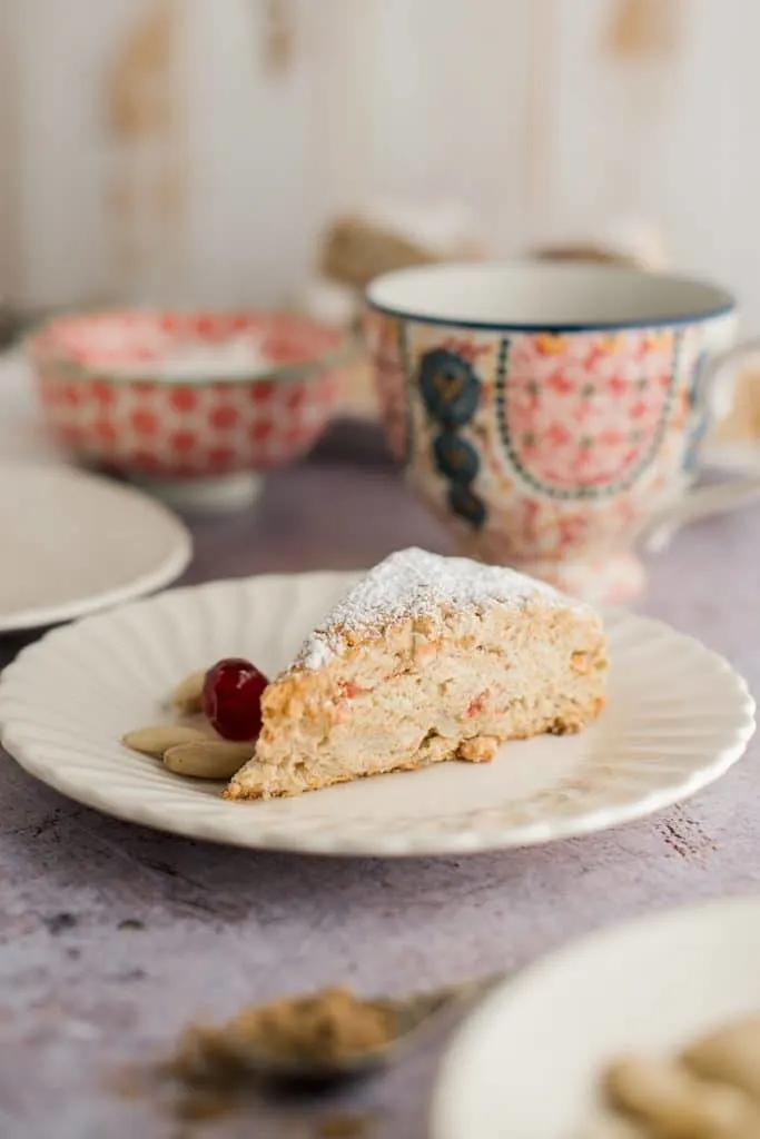 scone on a plate with coffee cup behind it