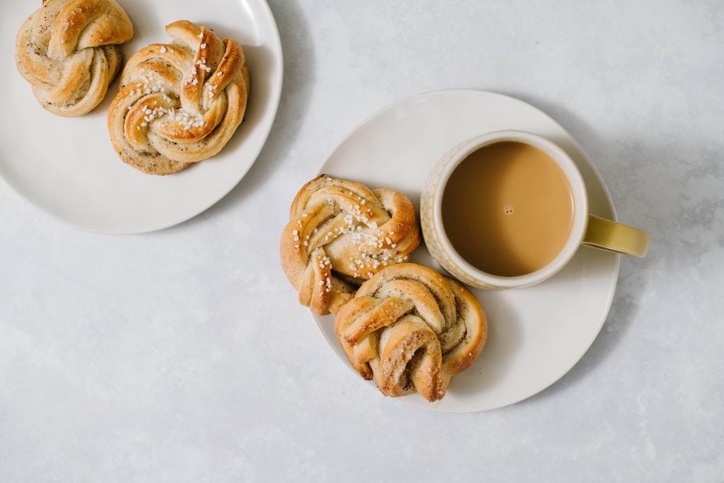 four cardamom buns on two plates with coffee cup