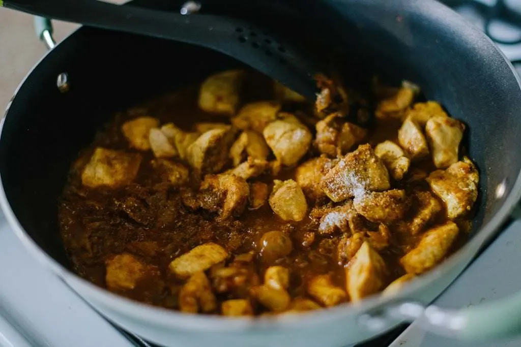 chicken added to curry in pan