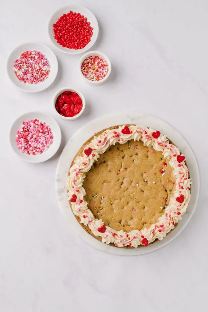 valentines cookie cake with five bowls of sprinkles