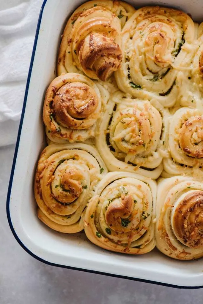 pull apart rolls with garlc butter in white ceramic baking dish with white towel