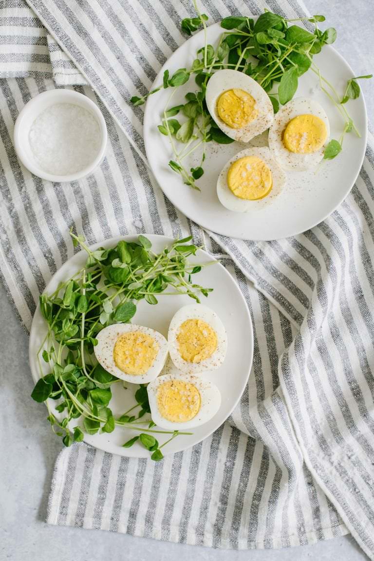 hard boiled eggs with microgreens on white plates