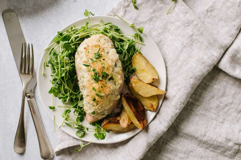 easy weeknight chicken breast with greens and potatoes on white plate with fork and knife
