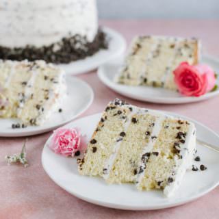 three slices of yellow cake with chocolate chips and buttercream on white plate with cake in background