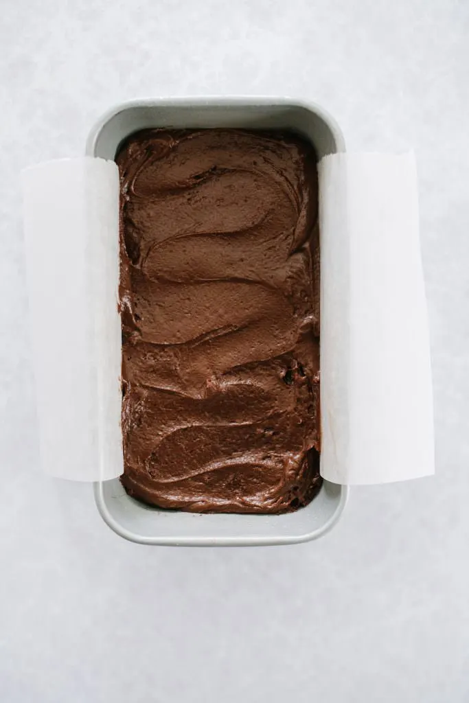 chocolate cake batter in parchment lined loaf pan