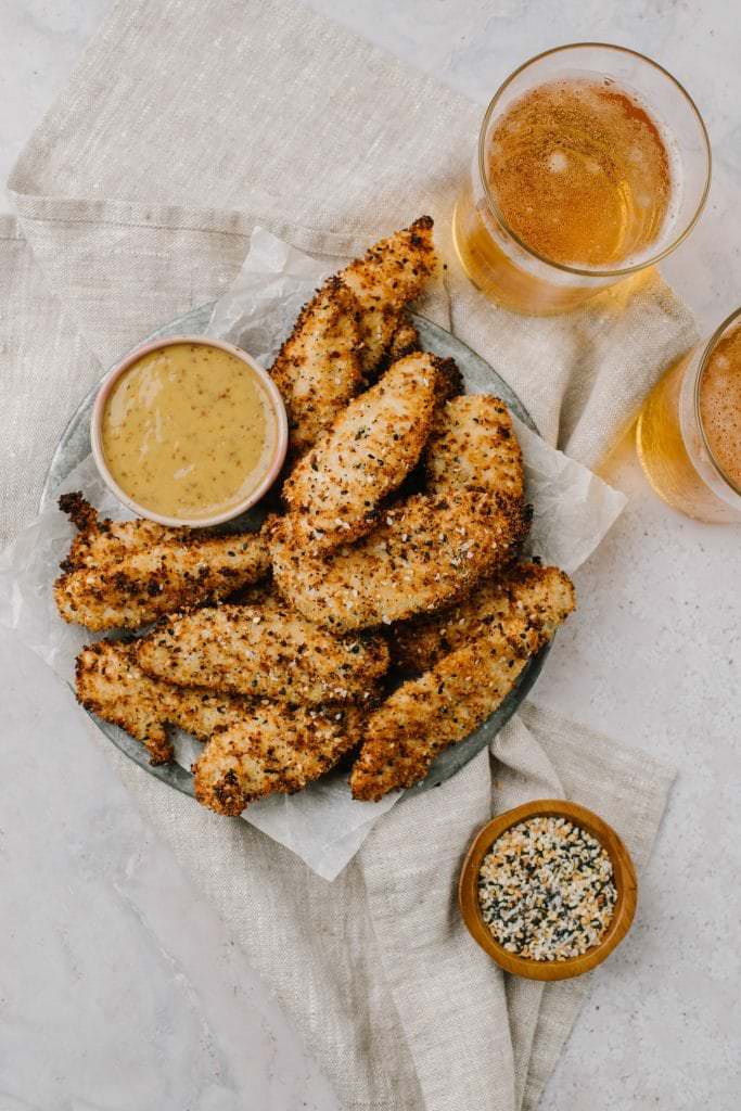 a plate of air fryer everything chicken finger with honey mustard dip and two beers