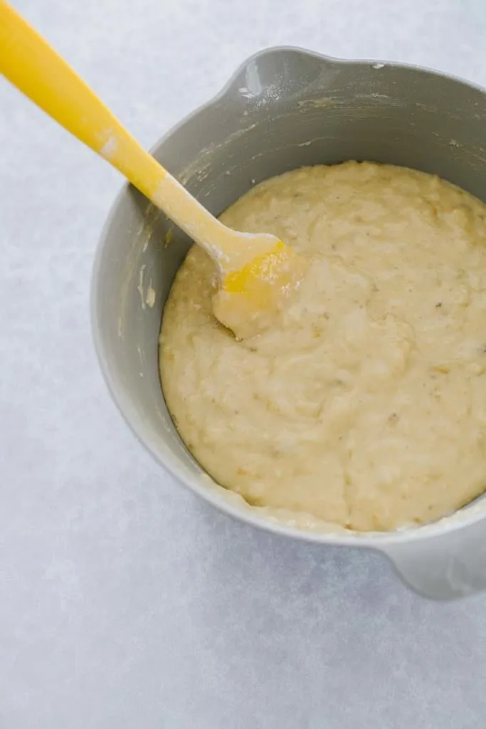 banana bread batter in mixing bowl with yellow spatula
