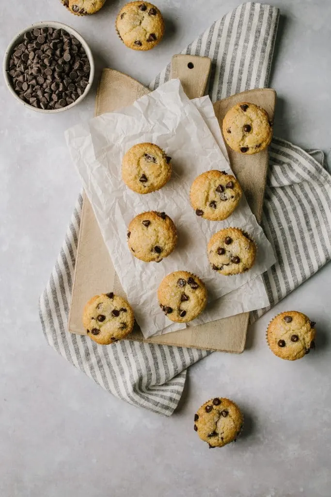 the best chocolate chip muffins on a table with a bowl of chocolate chips