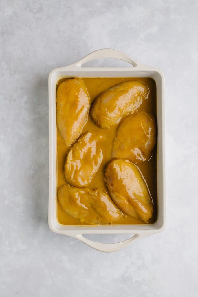 chicken breasts in sweet and savory sauce in white baking dish