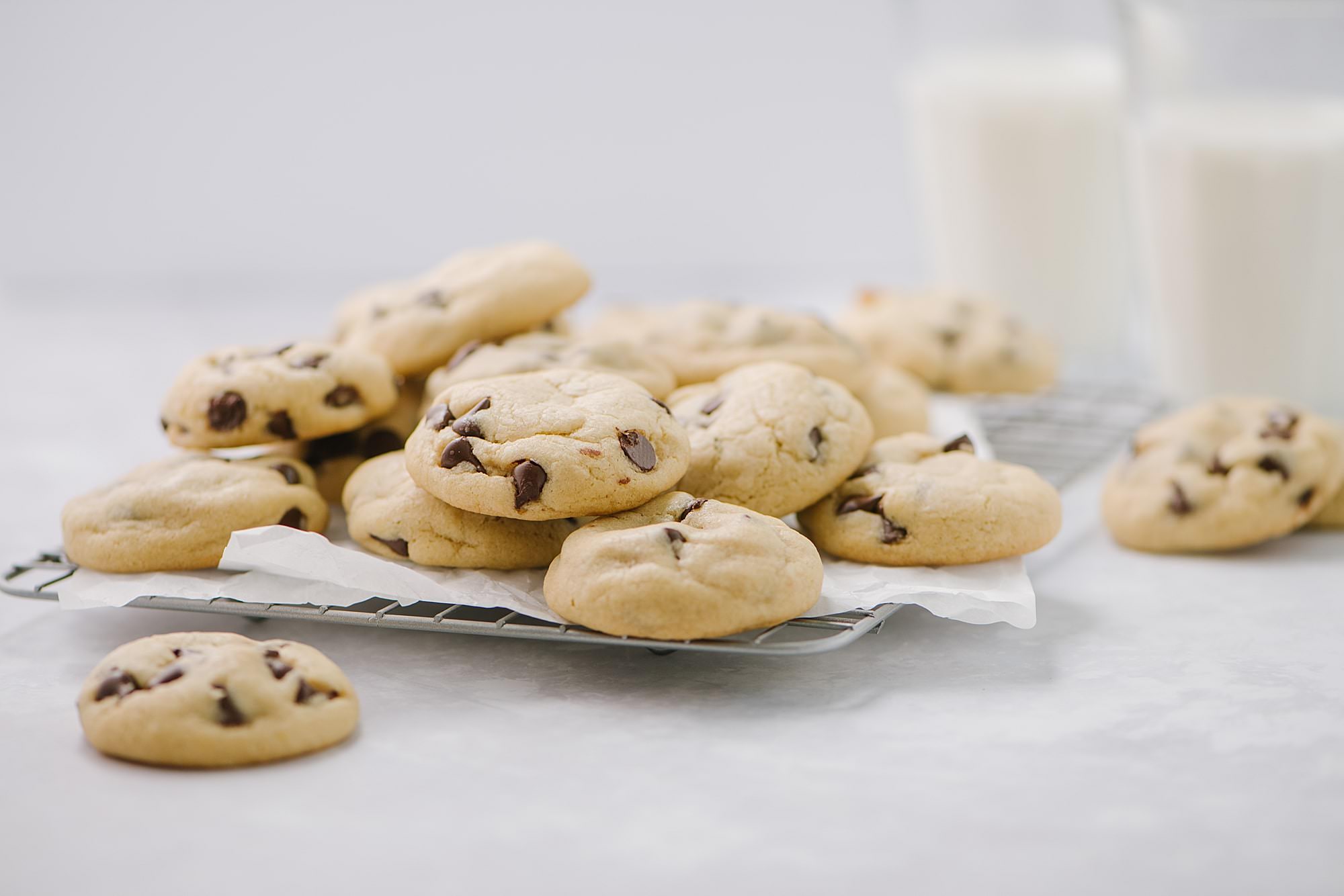 cookies with chocolate chips on cooling rack with a glass of milk