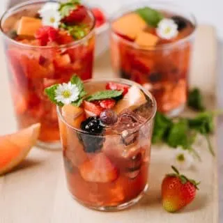 close up shot of three glasses of rose sangria with strawberries blueberries raspberries blackberries and grapefruit