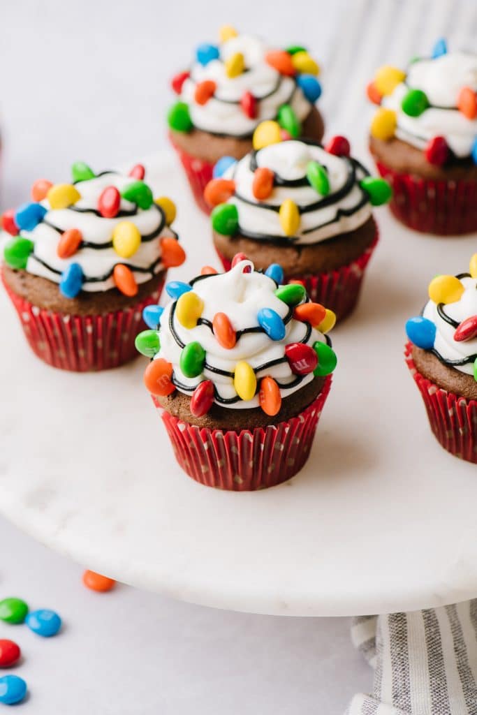 chocolate cupcakes decorated with vanilla frosting, black strings and m&ms