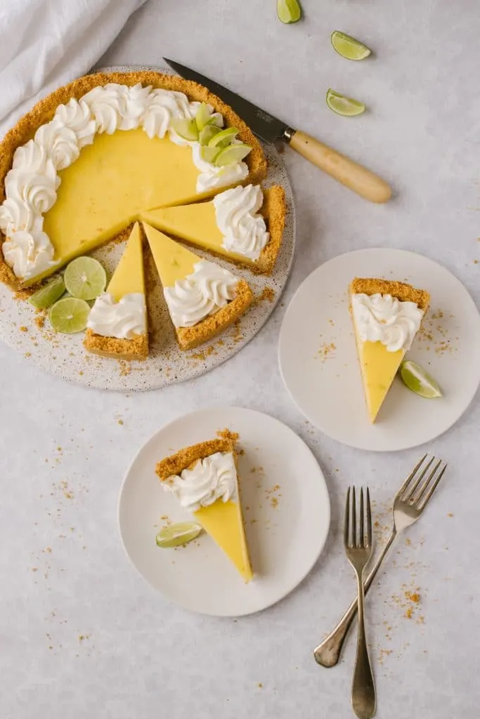 slices of the best key lime pie recipe on white plates with forks and whole pie on the side