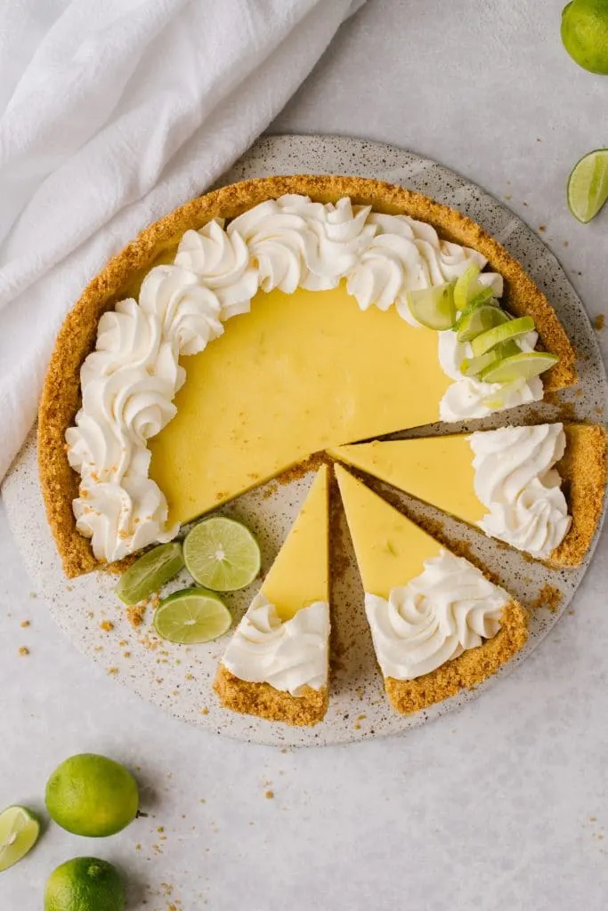 easy key lime pie recipe topped with whipped cream and sliced with fresh limes on the side