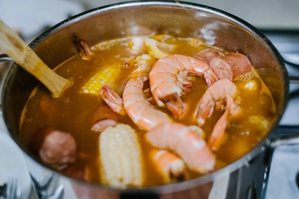 shrimp and corn simmering in spicy stock in pot