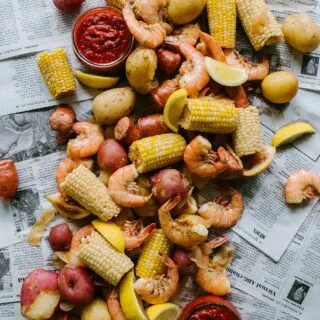 pile of shrimp, sausage, corn, potatoes on newspaper