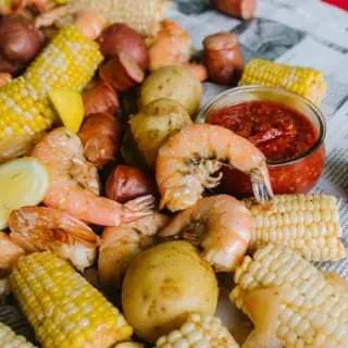 pile of shrimp, sausage, corn, potatoes on newspaper