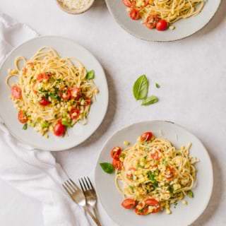 three plates of pasta with sweet corn gremolats and a small bowl of Parmesan