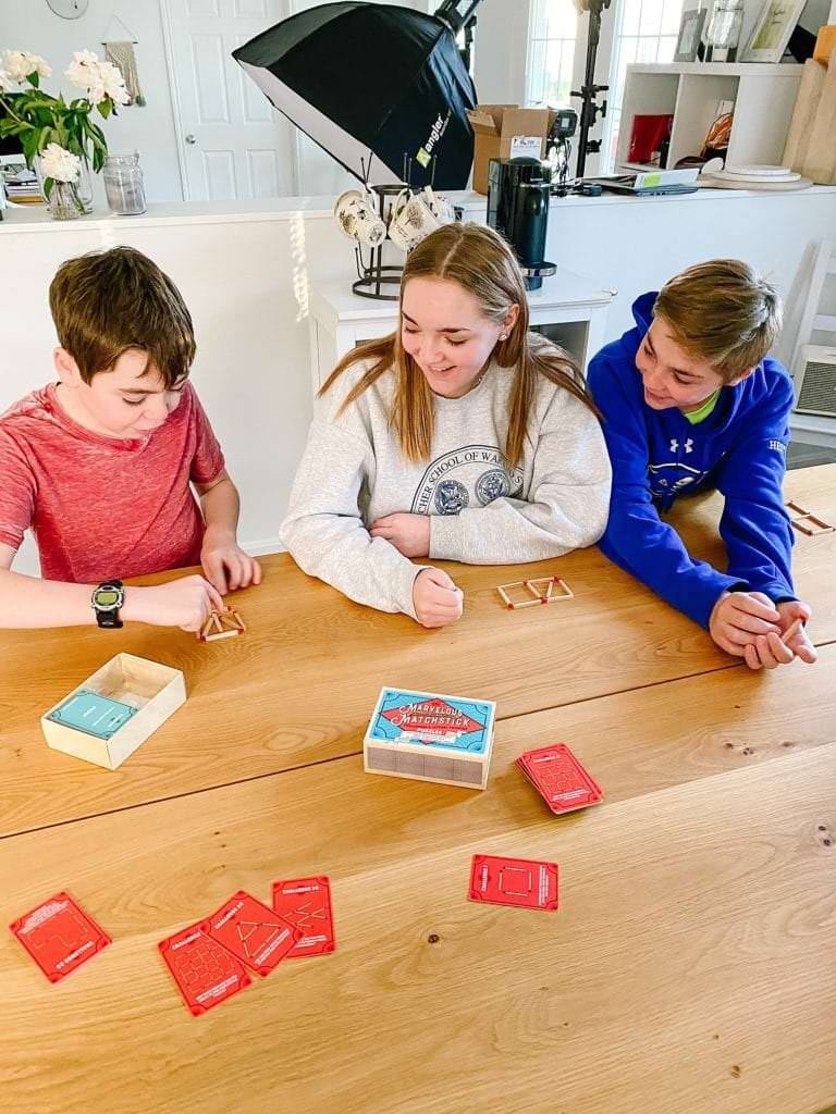 kids playing matchstick game around a table