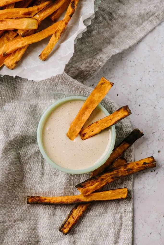 two sweet potato fries dipped in marshmallow sauce