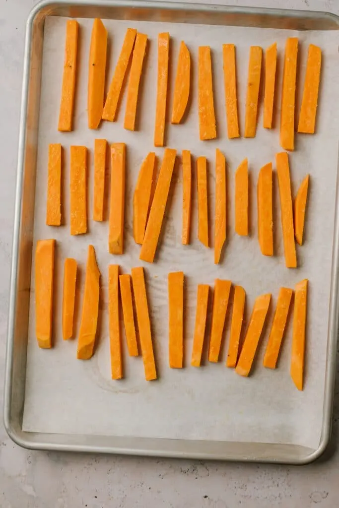 sweet potato batons lined up on baking sheet